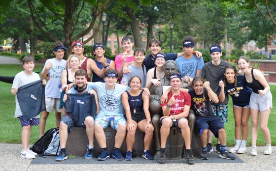 a group of teens outside sitting on a bench smiling at the camera