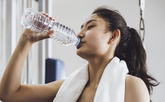 Person drinking from water bottle in gym