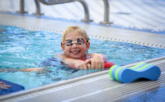Child wearing goggles swimming in the pool