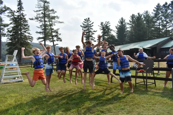 a group of campers jump for joy as they get ready to enjoy an afternoon on the lake