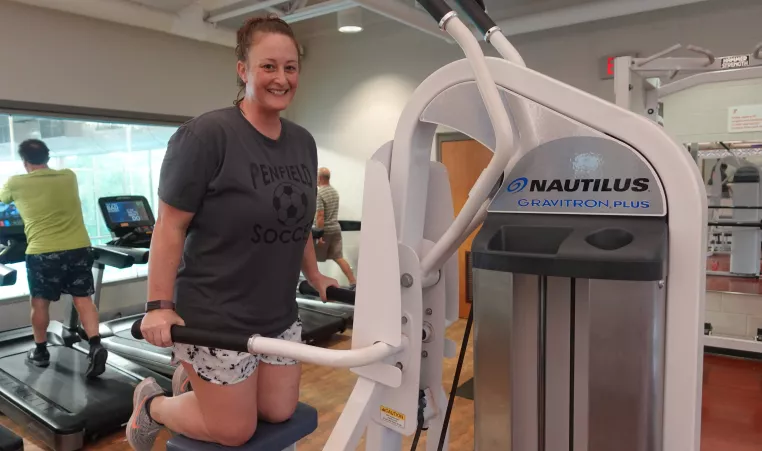 Woman working out on a nautilus gravitron plus, smiling at the camera