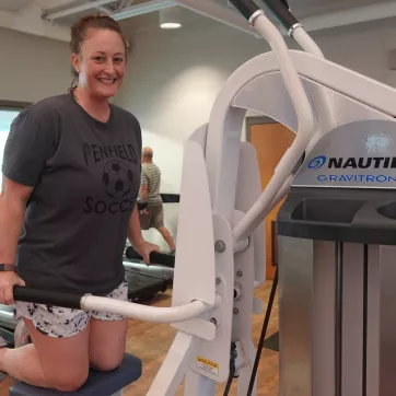 Woman working out on a nautilus gravitron plus, smiling at the camera