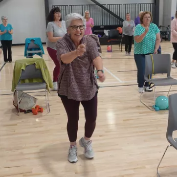 active older adult in a silver sneakers class moving and smiling towards camera