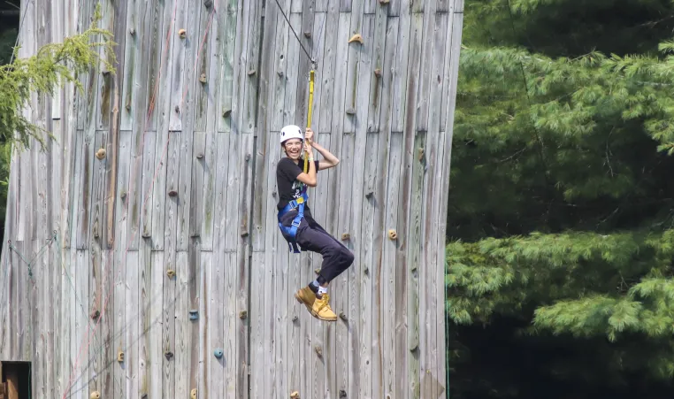 a camper glides down the zipline with a big smile